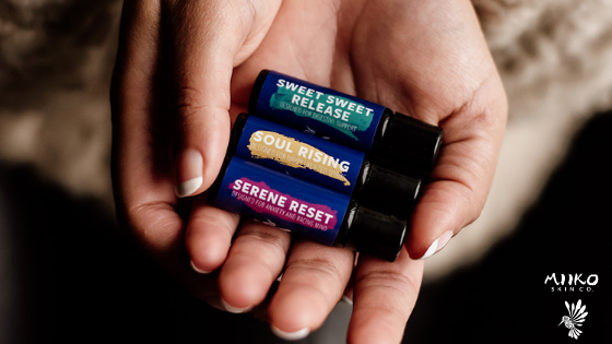 Hands holding three essential oil roll-ons